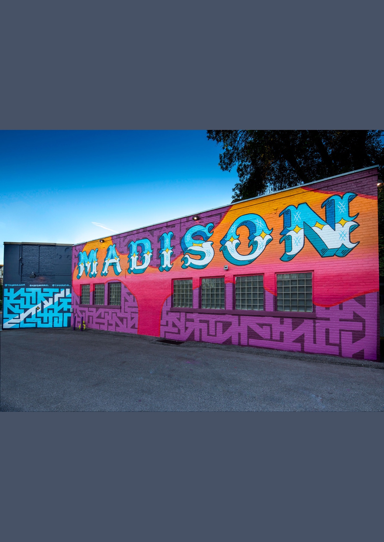 pintura feira no muro com cores roxo, azul e laranja predominante